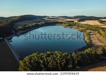 Aerial photo of the peaceful and idylic blue lake on sunset. Drone shot from above - trees and blue lake in Europe - Slovakia.