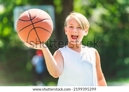 A portrait of a boy kid playing with a basketball in park