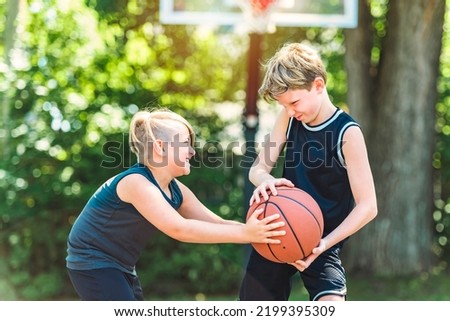 A portrait of two boys kids playing with a basketball in park