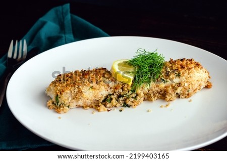 Walnut-Crusted Halibut in Lemon Wine Sauce Viewed from the Side: Baked white fish fillet garnished with fresh dill and a slice of lemon Royalty-Free Stock Photo #2199403165