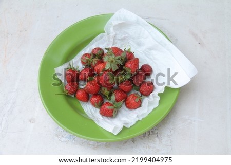 fresh strawberries on a green plastic plate after washing