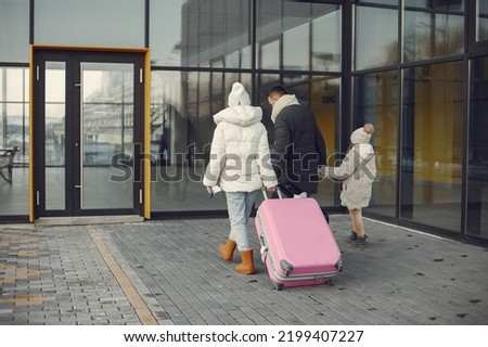 Mother, father and daughter with luggage going to airport terminal