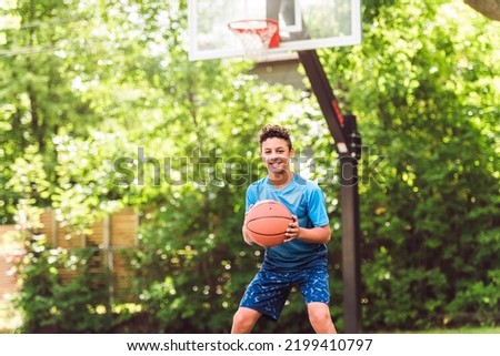 A teen boy play basketball on summer season