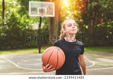 A girl with basketball on court on summer season
