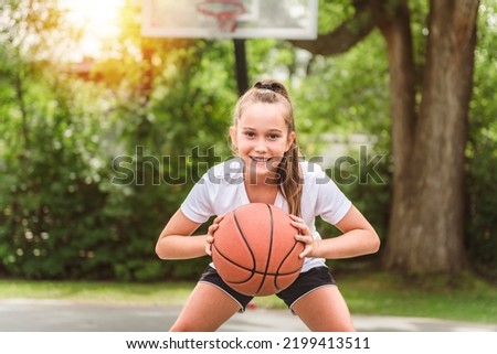 A girl with basketball on court on summer season