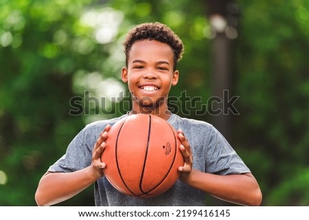 A portrait of a boy kid playing with a basketball in park