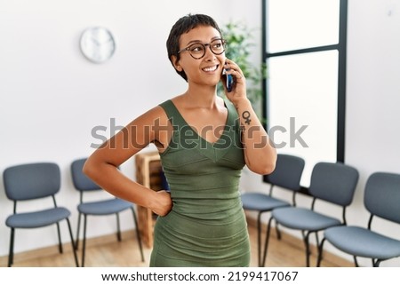 Young hispanic woman smiling confident talking on the smartphone standing at waiting room