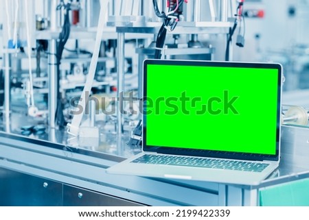 computer laptop blank green screen on science lab advance machine automation engineering tech industry concept background.