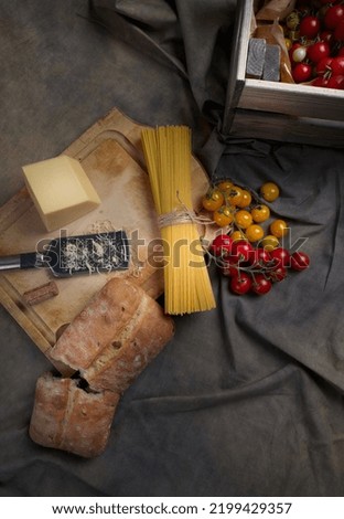 Wood box with cherry tomatoes and spaghetti on the textile table top.