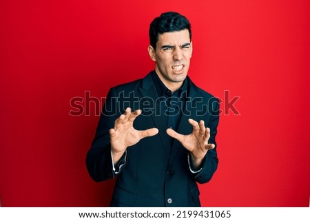Handsome hispanic man wearing business clothes disgusted expression, displeased and fearful doing disgust face because aversion reaction. with hands raised 