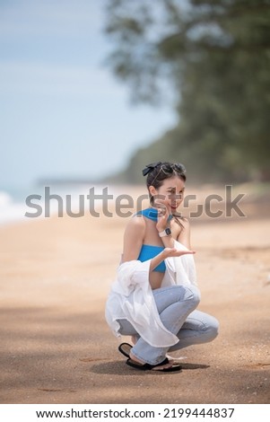 Woman picking up shells and holding them in hand on the beach.