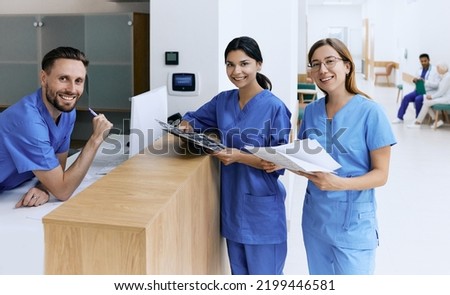 Nurse on duty talking with medical assistants during working day in medical clinic standing near reception desk at hospital lobby. Medical staff of clinic Royalty-Free Stock Photo #2199446581