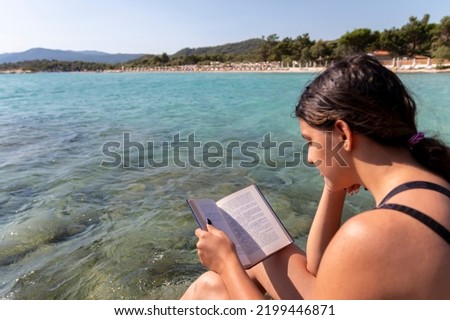 Teen girl reading a book and relaxing at the beach