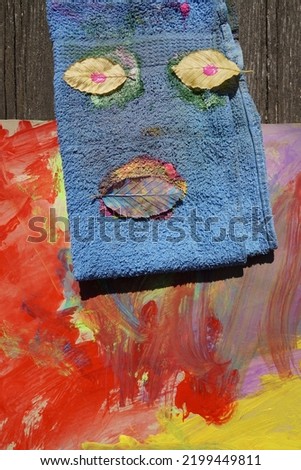 Blue Hand Towel As Funny Face And Colorful Blobs On The Table. 