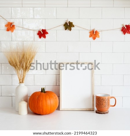 Mockup frame with pumpkin, candle, coffee cup, vase of wheat in cozy home interior with autumn fall decorations. Thanksgiving, Halloween holiday poster design.