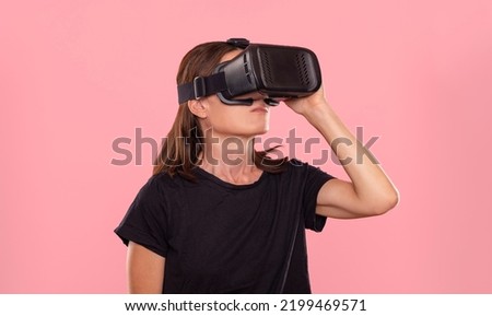 Woman wearing virtual reality headset, pink background