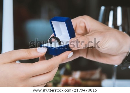 Man gives a woman payments smart ring.  Romantic dinner. Male hands with blue velvet box containing payments smart ring. Valentine day