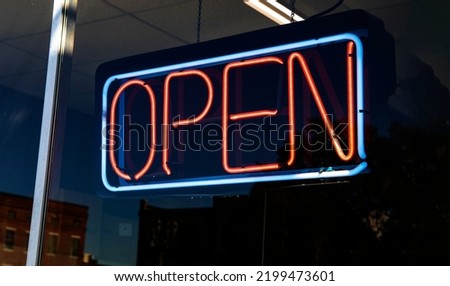 Neon OPEN sign hanging in a retail store window USA