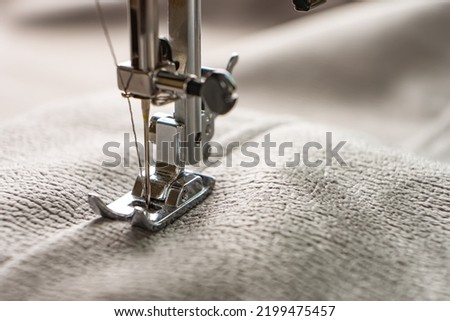 Modern sewing machine presser foot with gray fabric and thread, closeup, copy space. Sewing process clothes, curtains, upholstery. Business, hobby, handmade, zero waste recycling, repair concept, DIY
