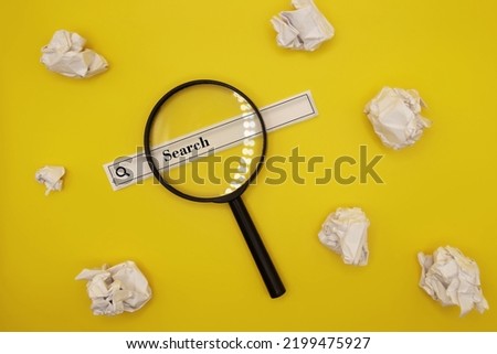 magnifying glass, web search tape text and crumpled papers yellow background