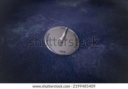 Steel chromed polished spinning top decision maker on a deep blue stone background