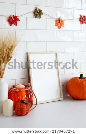 Mockup picture frame with autumn decorations, pumpkins on white table. Fall, Thanksgiving, Halloween concept. 
