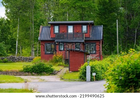 Small red and black house near a forest.