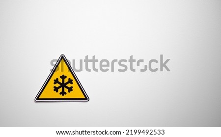 A triangular sign with a snowflake on a white isolate. Danger of freezing. A cold temperature sign on a white background. Precipitation in the form of snow emblem.