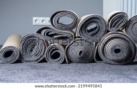 Stacked old carpet rolls in a grey room. Royalty-Free Stock Photo #2199495841