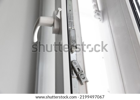 Close-up of a double-glazed balcony frame with a latch and fastening for safe ventilation. Single-sided window handle. Royalty-Free Stock Photo #2199497067