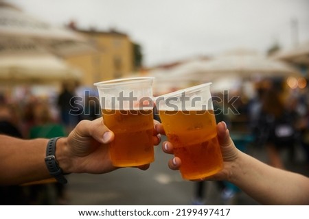 Men are clinking glasses with light beer over a table with beer snacks, in a pub with neon lights Royalty-Free Stock Photo #2199497417