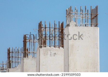 Freshly poured concrete pillars in a high rise construction project showing rebar reinforcing steel at the top for the next pour Royalty-Free Stock Photo #2199509503