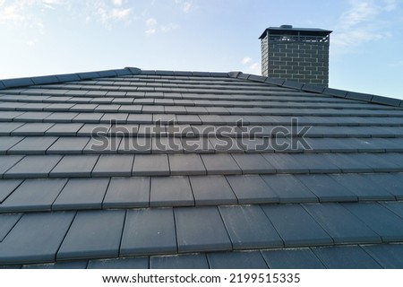 Closeup of house roof top covered with ceramic shingles. Tiled covering of building Royalty-Free Stock Photo #2199515335