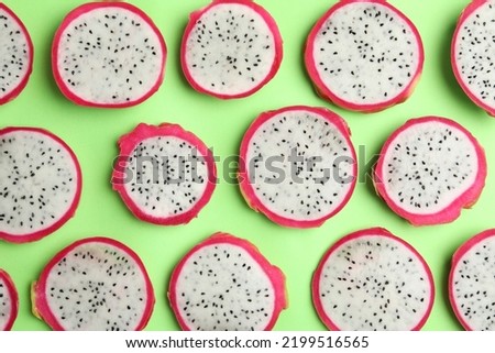 Slices of delicious dragon fruit (pitahaya) on green background, flat lay