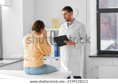 medicine, healthcare and people concept - male doctor with clipboard and fe male patient having health problem at hospital Royalty-Free Stock Photo #2199528211