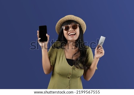 Traveler  asia woman she in summer clothes hat hold credit card and  ticket mobile cell phone isolated on blue  background, summer vacation concept ads