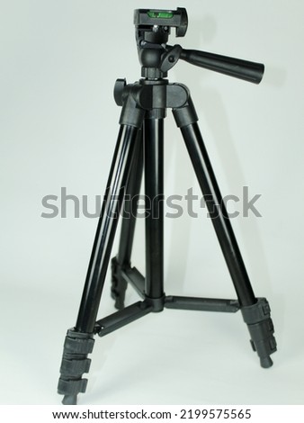 Black textured mini tripod made of plastic and metal on a white background