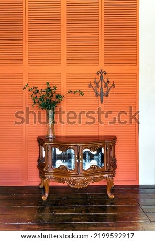 Stylish living room interior design with retro wooden chest of drawers. Orange or terracotta walls. Home decor. High quality photo
