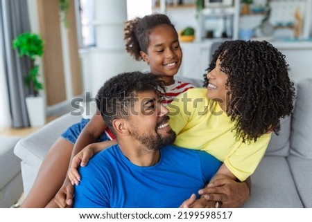 Positive cheerful multi-ethnic family wife husband child sitting together on couch at home. Close up focus on little daughter and beautiful mother. Happy multiracial family concep