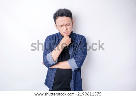Portrait of a thoughtful young Asian man wearing navy blue shirt looking aside wondering choices