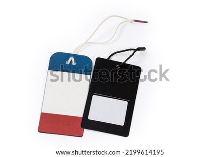 Blank clothing swing tags in the form of red blue and black carton sheets on a ropes on a white background
