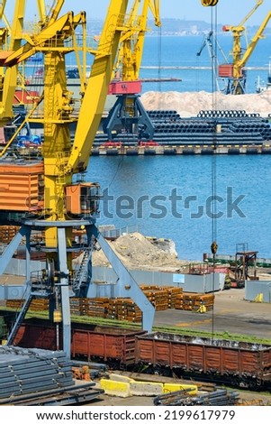 industrial seaport infrastructure - sea, cranes and metal workpieces, bundles of wire, railcars on railroad, concept of marine cargo transportation