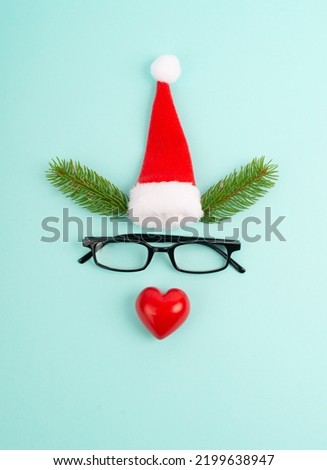 Face of a reindeer with a red heart nose, fir antlers, a santa claus hat and eyeglasses, merry christmas greeting card 