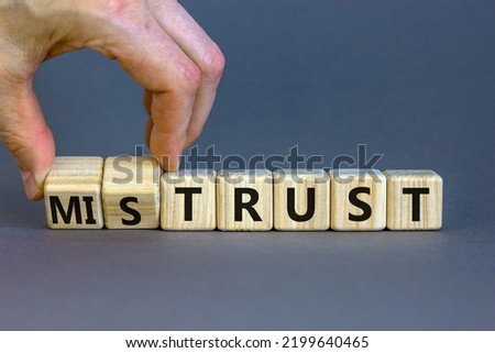 Mistrust or trust symbol. Businessman turns wooden cubes, changes words 'mistrust' to 'trust'. Beautiful grey table, grey background. Business and mistrust or trust concept, copy space. Royalty-Free Stock Photo #2199640465