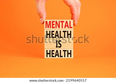 Mental health psychological symbol. Concept words Mental health is health on wooden blocks on a beautiful orange table orange background. Psychologist hand. Psychological mental health concept.