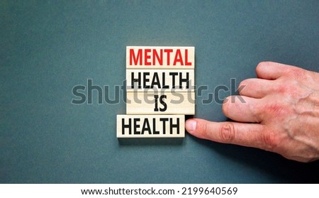 Mental health psychological symbol. Concept words Mental health is health on wooden blocks on a beautiful grey table grey background. Psychologist hand. Psychological mental health concept.