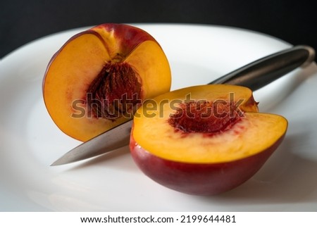 sliced nectarine on a white plate. kitchen knife. dark background
