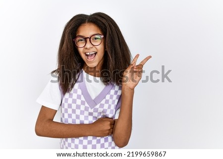 Young african american girl standing over isolated background smiling with happy face winking at the camera doing victory sign. number two. 