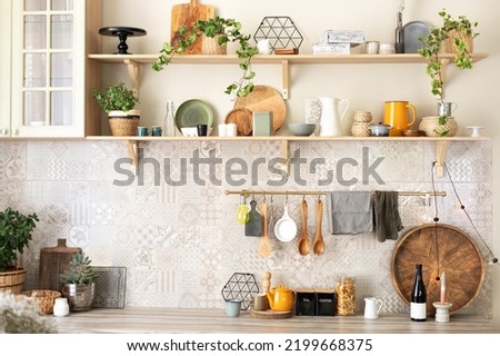 Stylish scandi cuisine interior decor. Ceramic plates, dishes, utensils and cozy decor on wooden shelfs. Kitchen wooden shelves with various ceramic jars and cookware. Open shelves in the kitchen.  Royalty-Free Stock Photo #2199668375