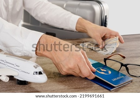 Male tourist checking passport and money while waiting for boarding, studio, light gray background